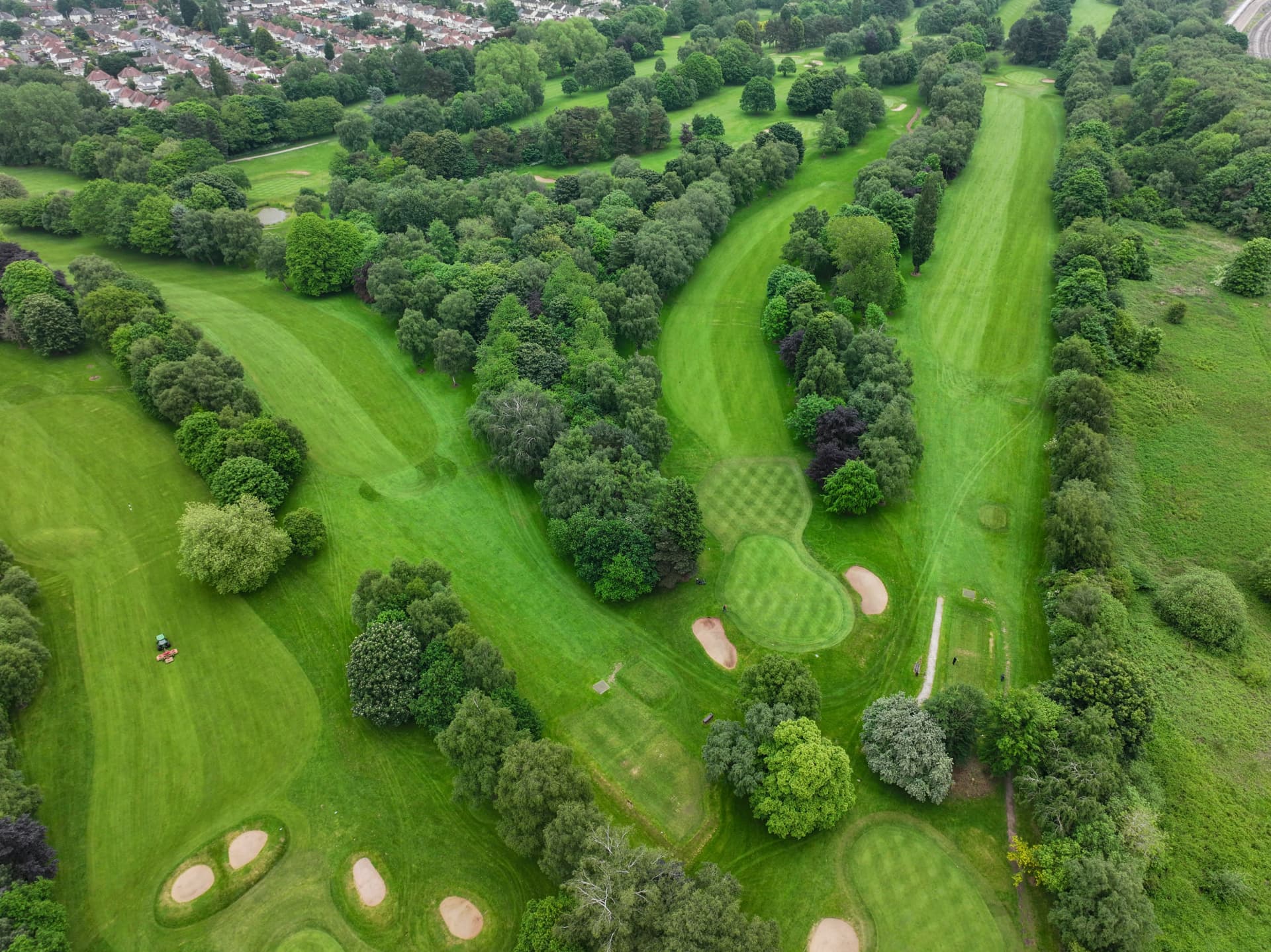 Aerial view of a golf course with tree-lined fairways, greens and sand bunkers